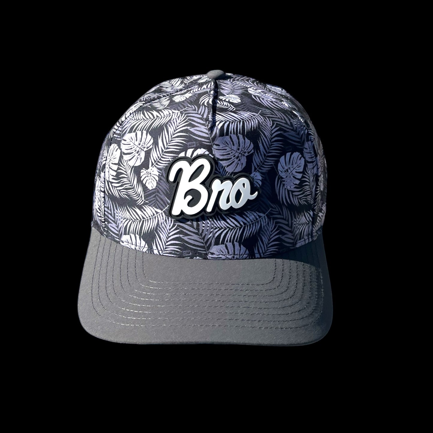 GolferBro performance snapback cap with tropical leaf print and white "Bro" logo. Features perforated panels and a grey bill.