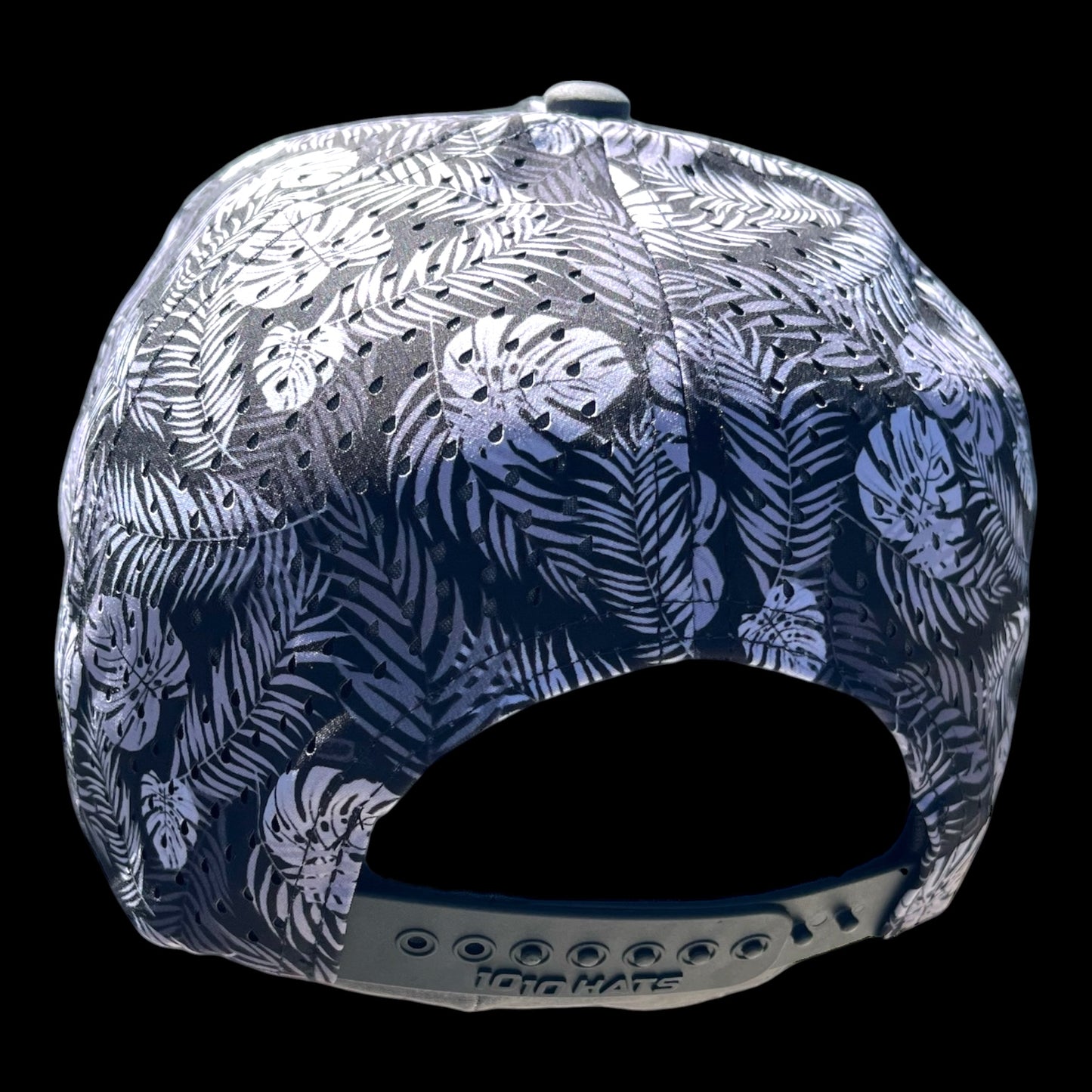 GolferBro perforated performance snapback cap with a tropical leaf print in black and white, featuring laser-cut side panels and a moisture-wicking sweatband.