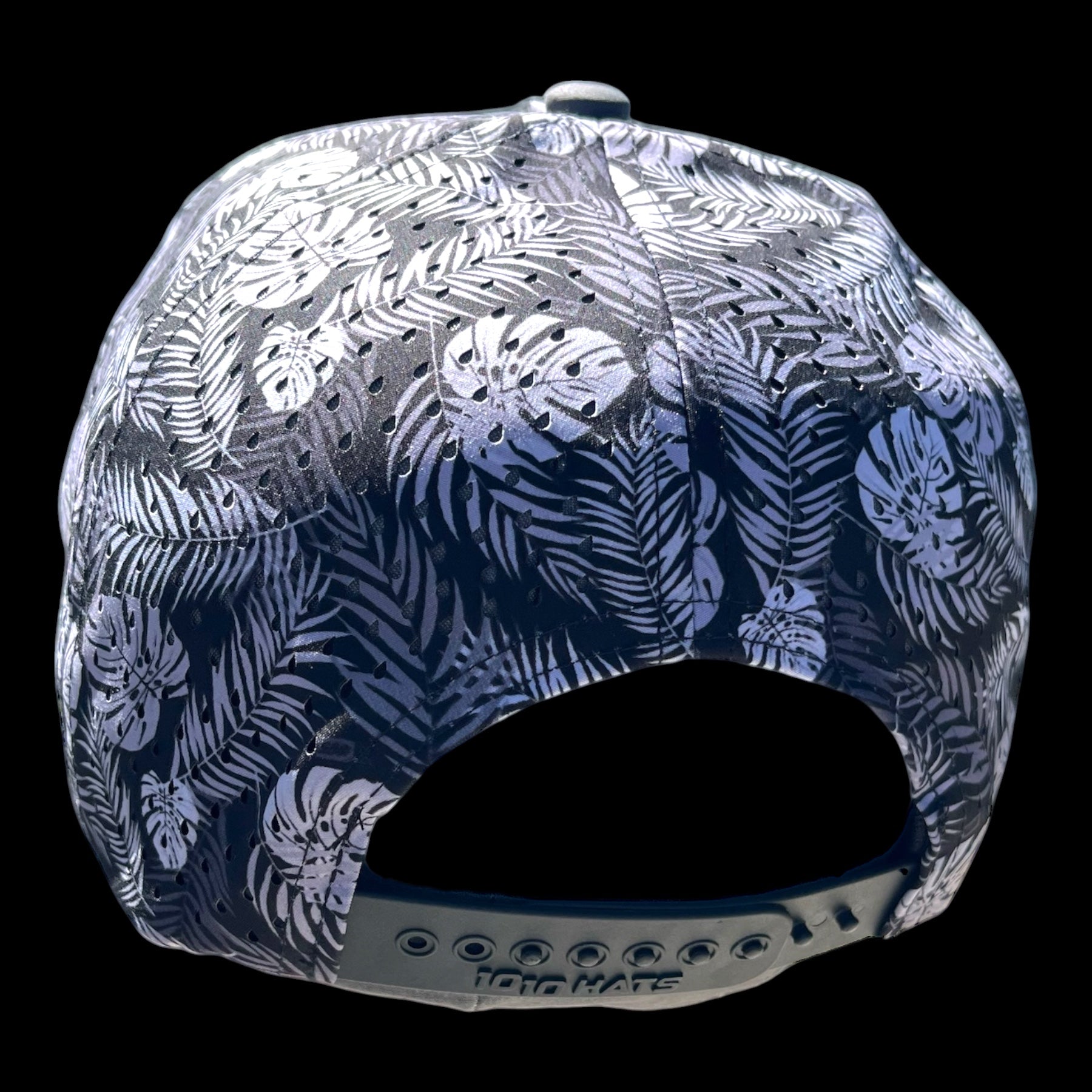 GolferBro perforated performance snapback cap with a tropical leaf print in black and white, featuring laser-cut side panels and a moisture-wicking sweatband.